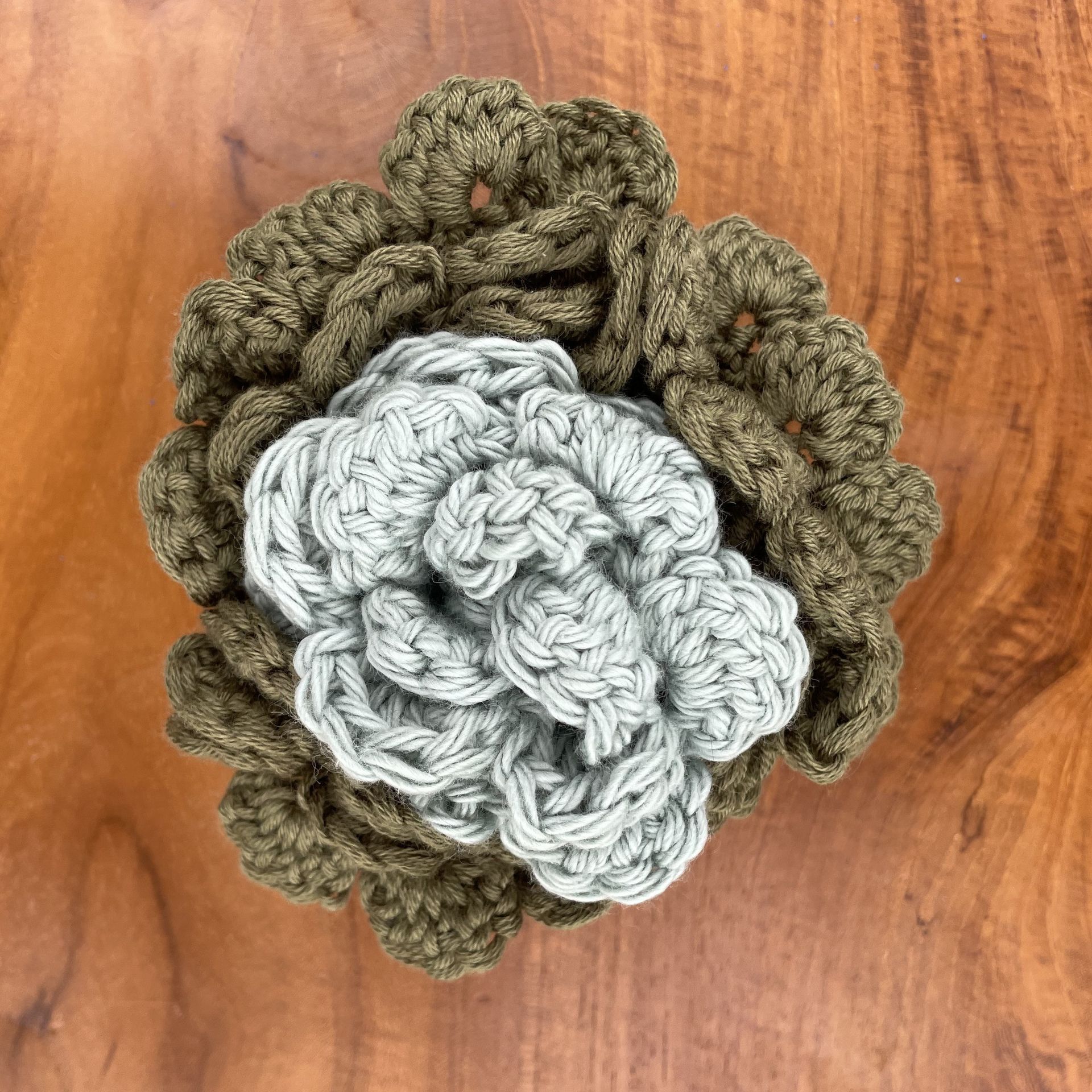 A close up of a crocheted flower on a brown background