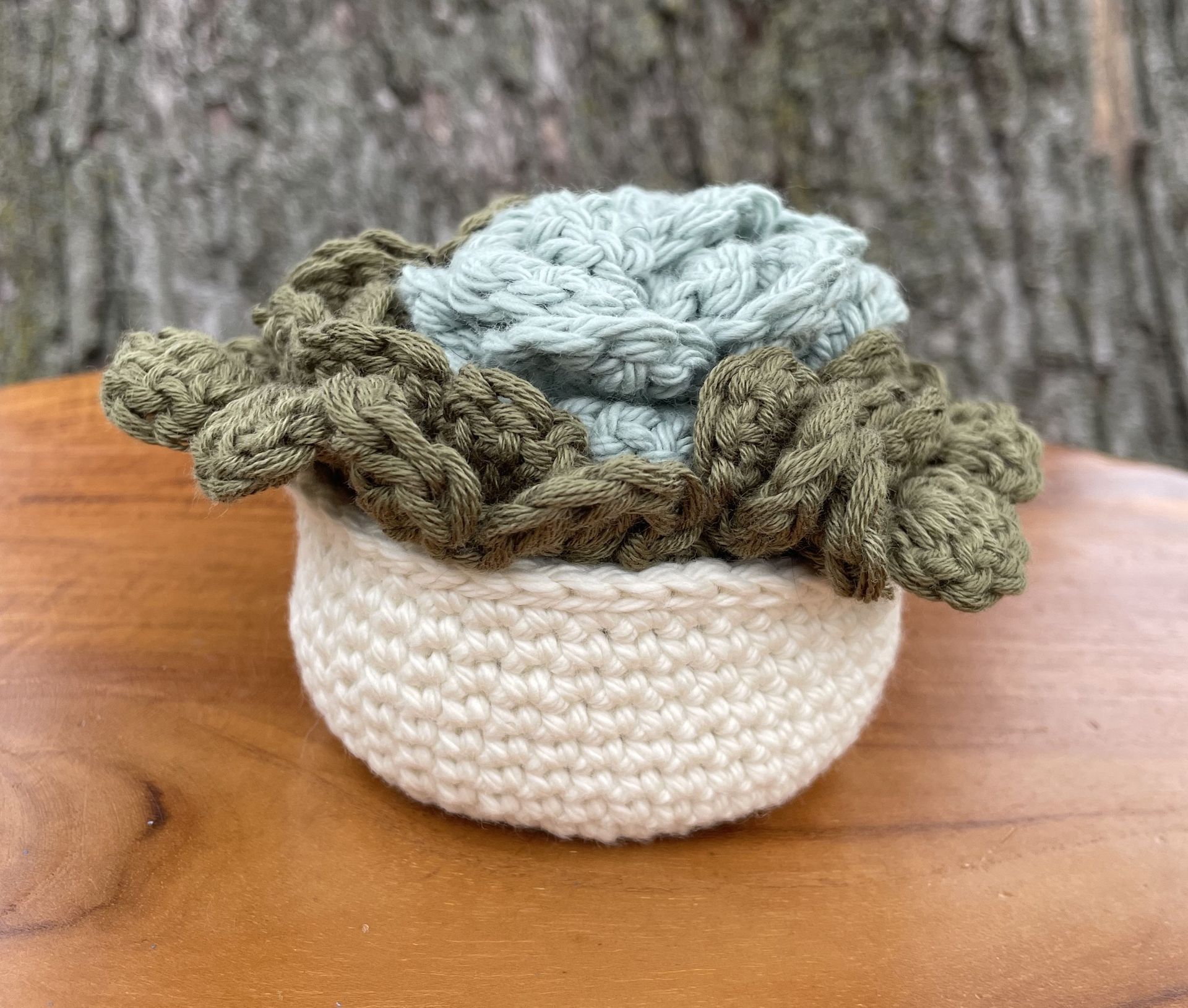 A person is holding a crocheted basket filled with yarn.