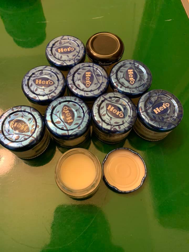 A group of body butter jars sitting on top of a green table.