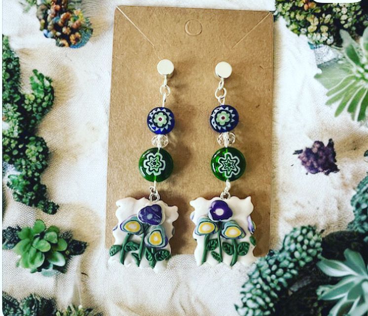 A pair of earrings with flowers and mushrooms on them