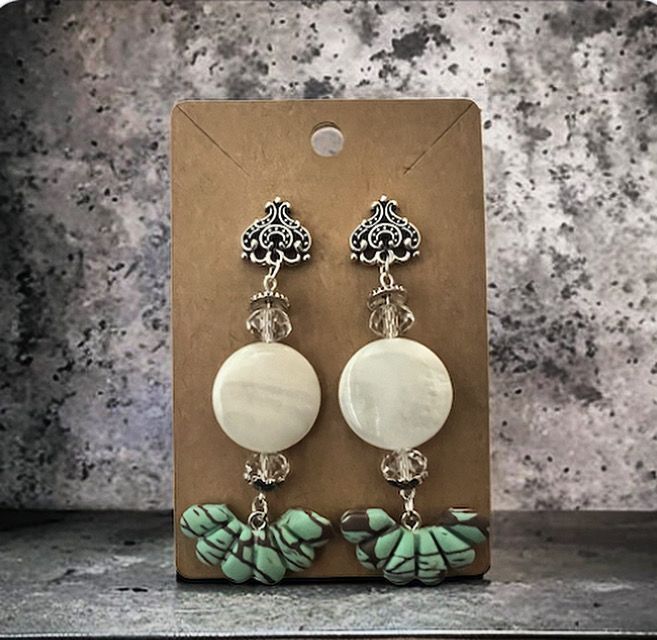 A pair of earrings are sitting on a cardboard holder.