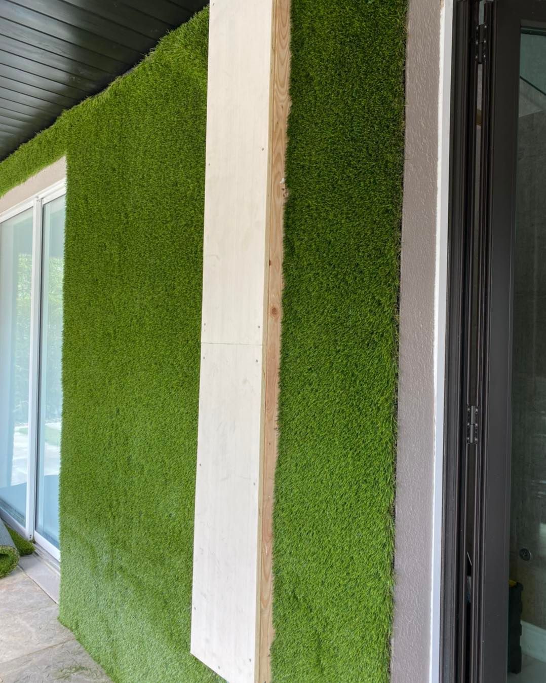 A wall covered in green grass next to a door.
