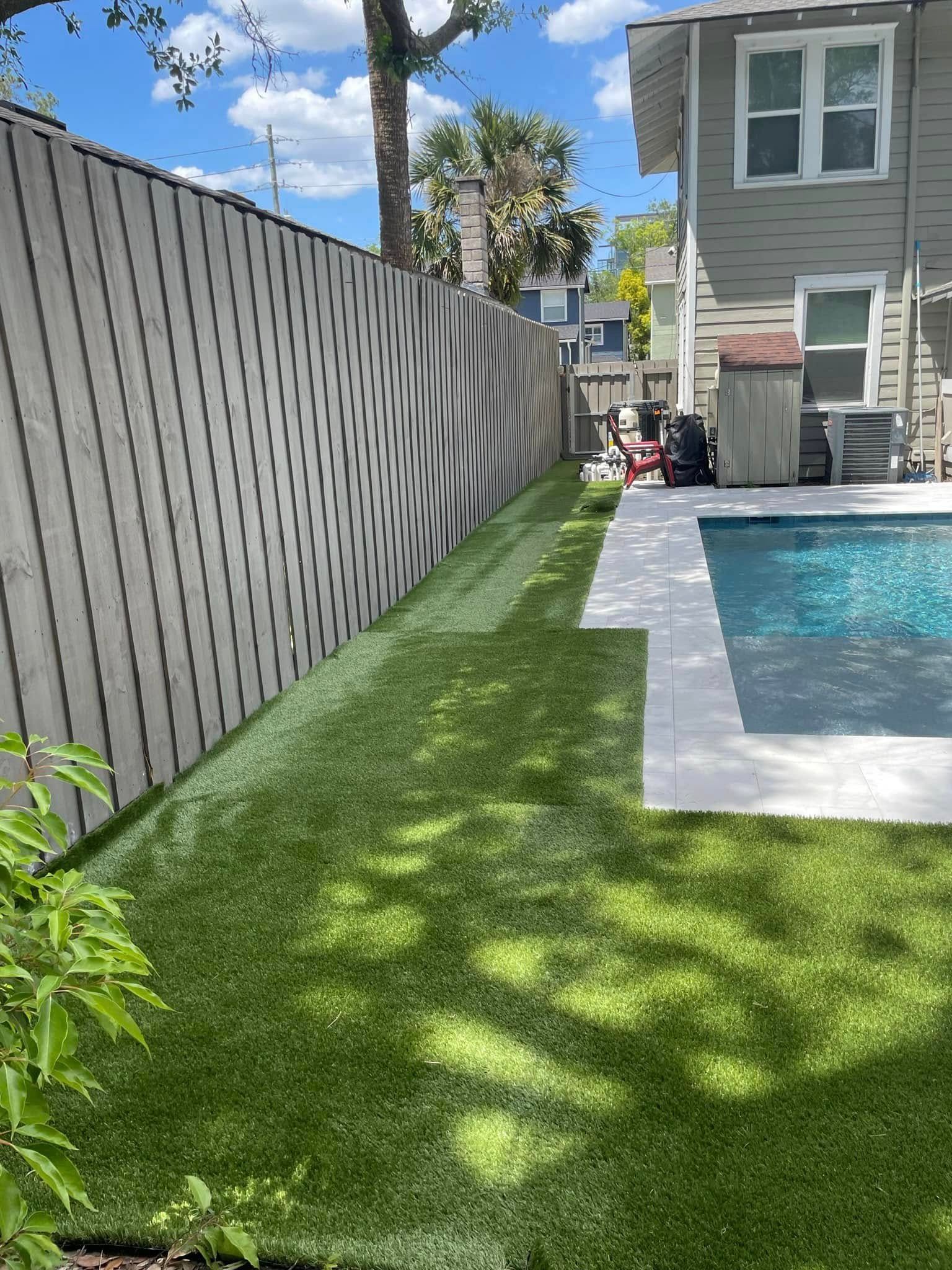 A fence surrounds a swimming pool in a backyard.