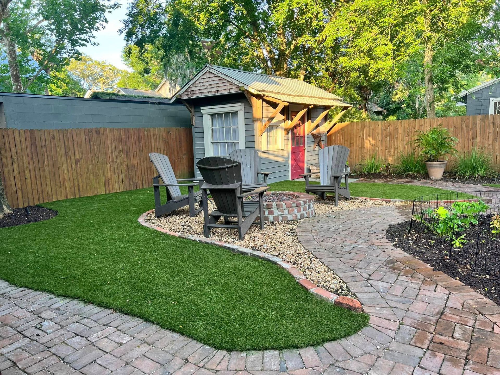 A backyard with a fire pit , chairs , a shed and a brick patio.