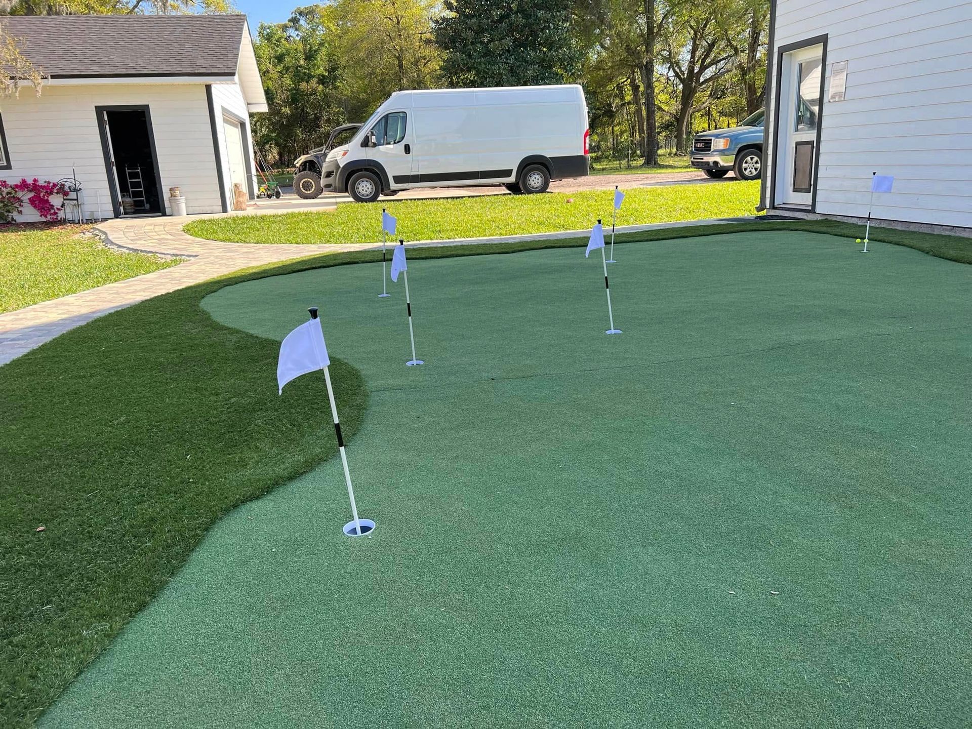 A white van is parked in front of a putting green.