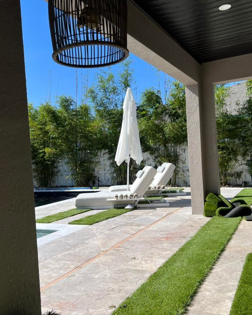 A patio with lawn chairs and a white umbrella