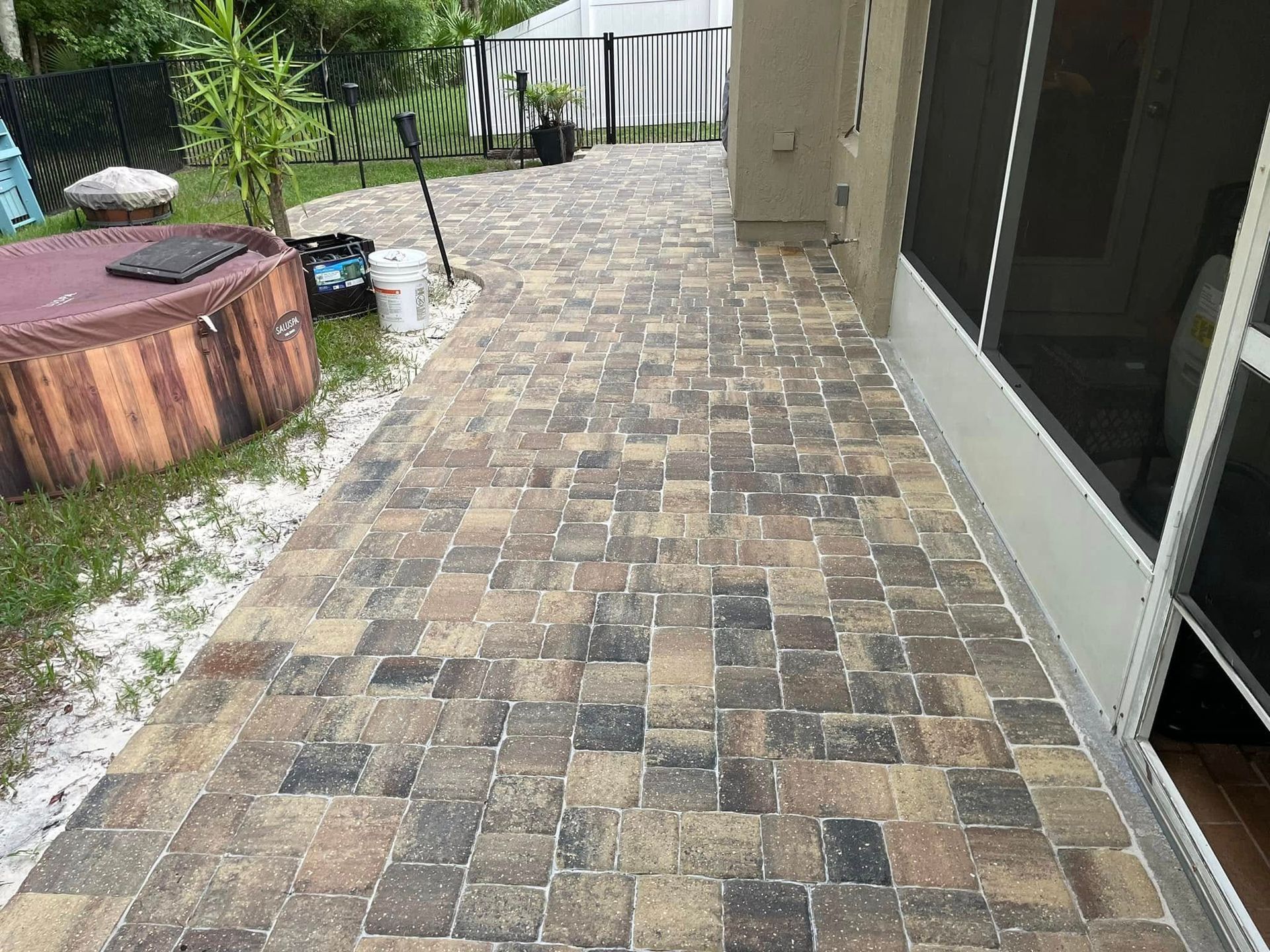 A patio with a hot tub and a screened in porch.