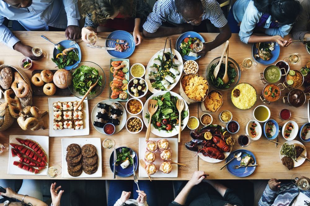 A Group Of People Are Sitting Around A Table Eating Food — Café and Restaurant in Cannonvale, QLD