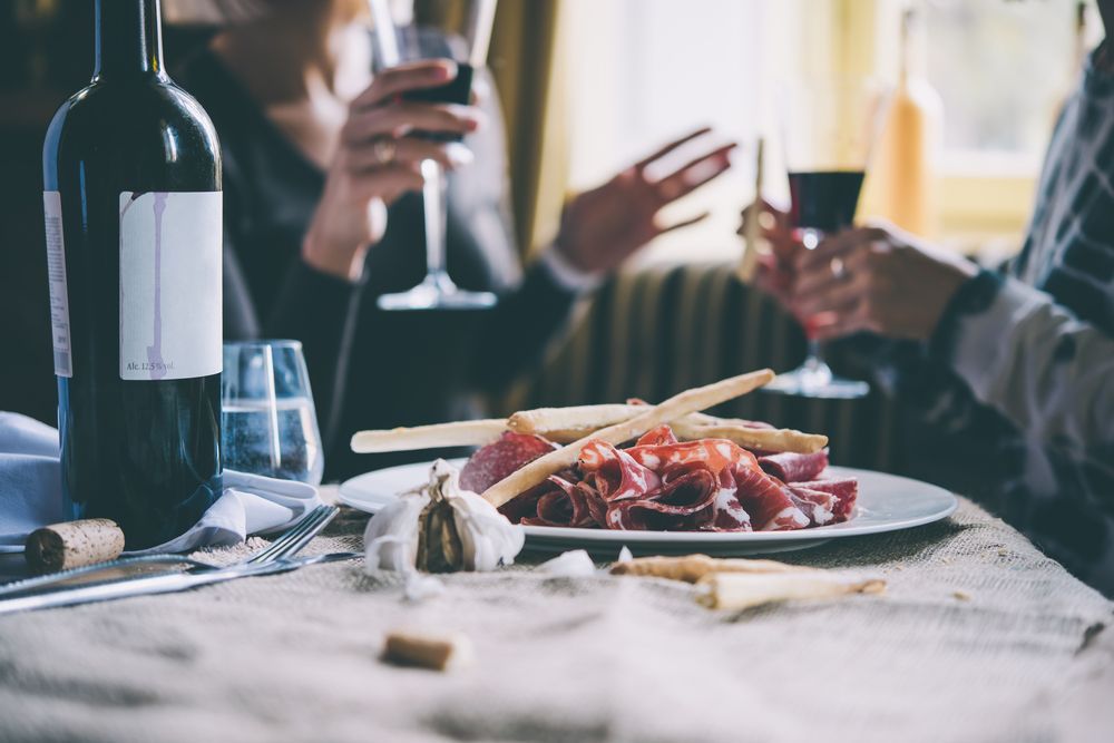 Group Of People Are Sitting At A Table With A Plate Of Food and A Bottle Of Wine — Café and Restaurant in Cannonvale, QLD