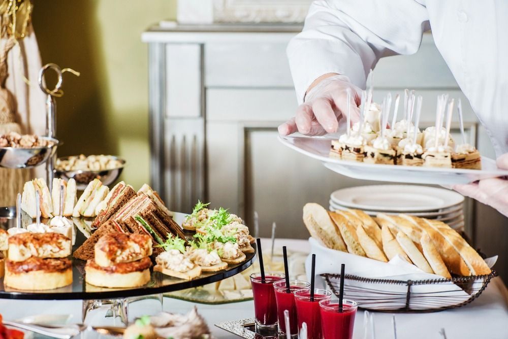 A Person Is Holding A Plate Of Food In Front Of A Buffet Table — Café and Restaurant in Whitsundays, QLD