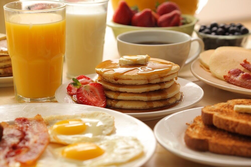 A Table Topped With Plates Of Food Including Pancakes Eggs Bacon And Toast — Café and Restaurant in Whitsundays, QLD