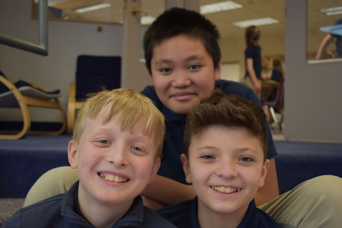 Three young boys are posing for a picture and smiling for the camera