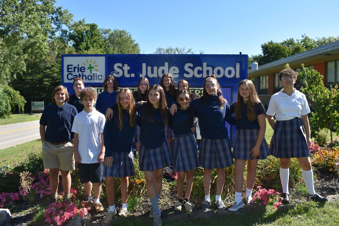 A group of children pose in front of a st. jude school sign