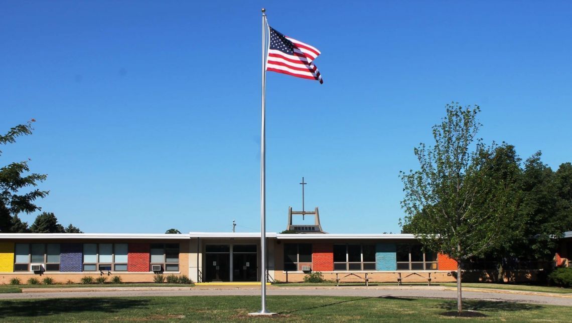 An american flag is flying in front of a school