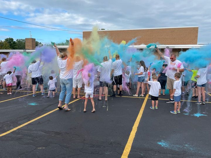 A group of people are standing in a parking lot covered in colored powder.
