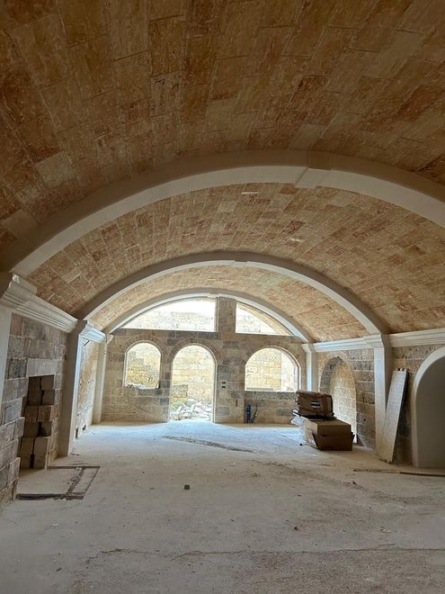 Una grande stanza con soffitto a volta e finestre ad arco.