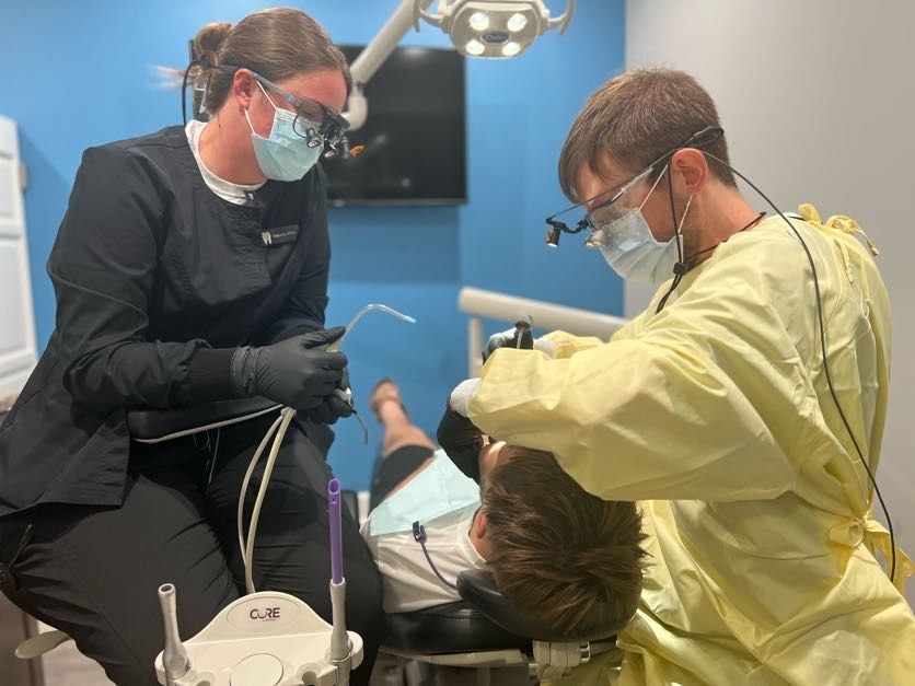 Dentist and assistant providing dental care to a patient in a clinic.