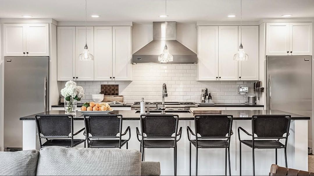 Modern kitchen with white cabinets, stainless steel appliances, black island, and bar stools.