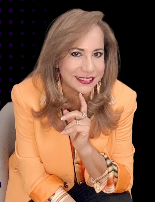 A woman in an orange jacket is sitting in a chair with her hand on her chin.