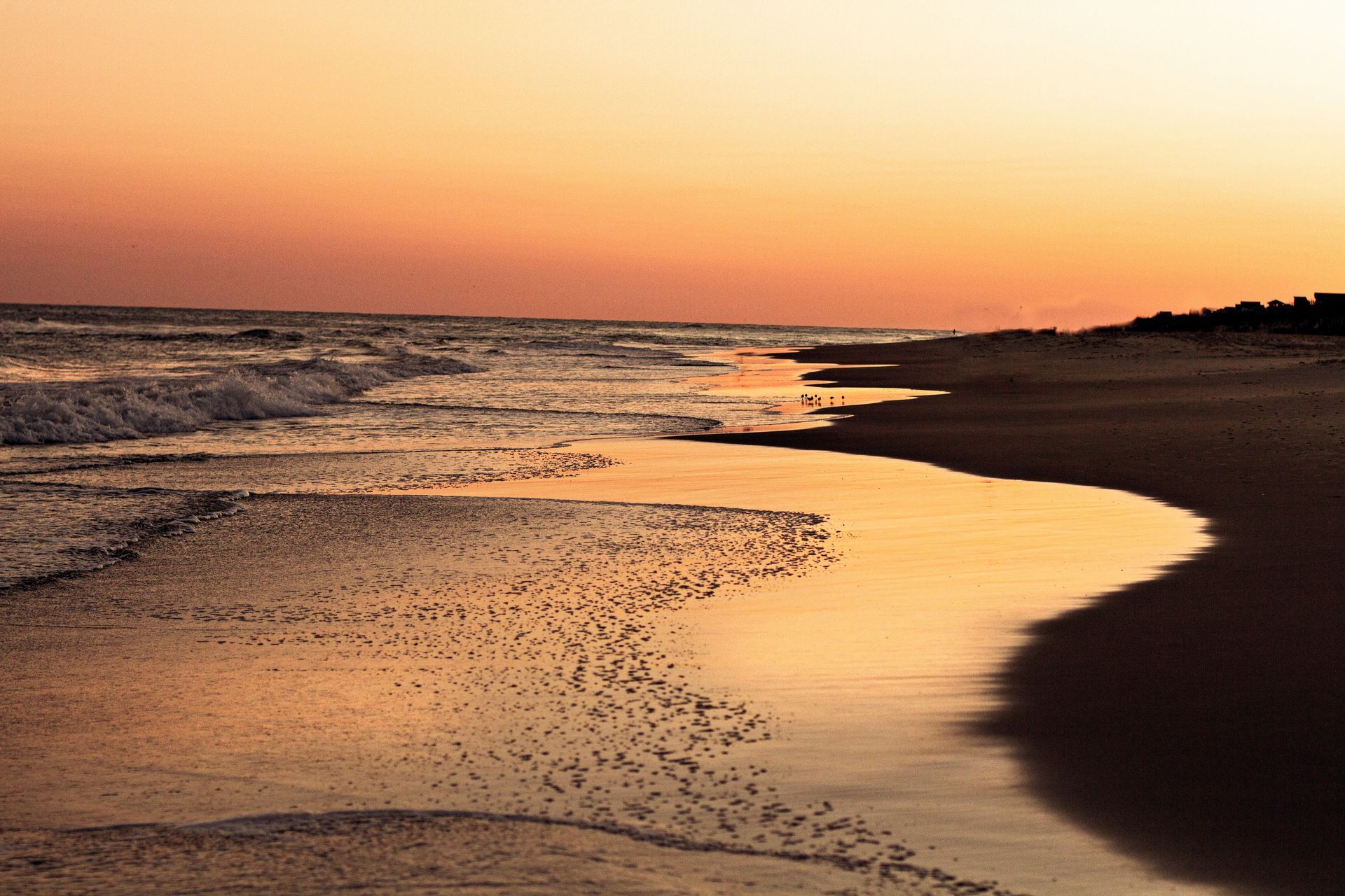 A beach at sunset with waves crashing against the shore