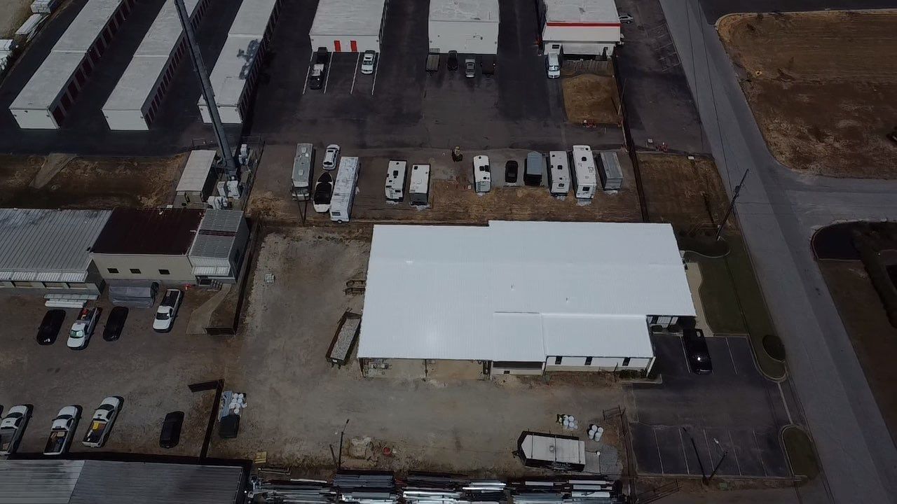Aerial view of a commercial property with buildings, RVs, vehicles, and a storage facility.