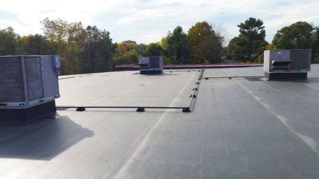 White metal roof with vents under a blue sky with clouds.