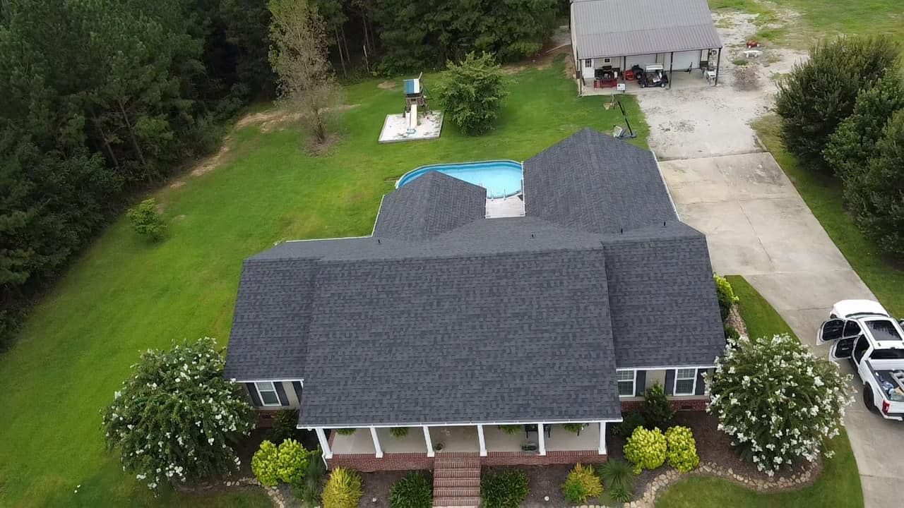 Close-up of a gray metal roof with matching gutters. Black fasteners and vents are visible.