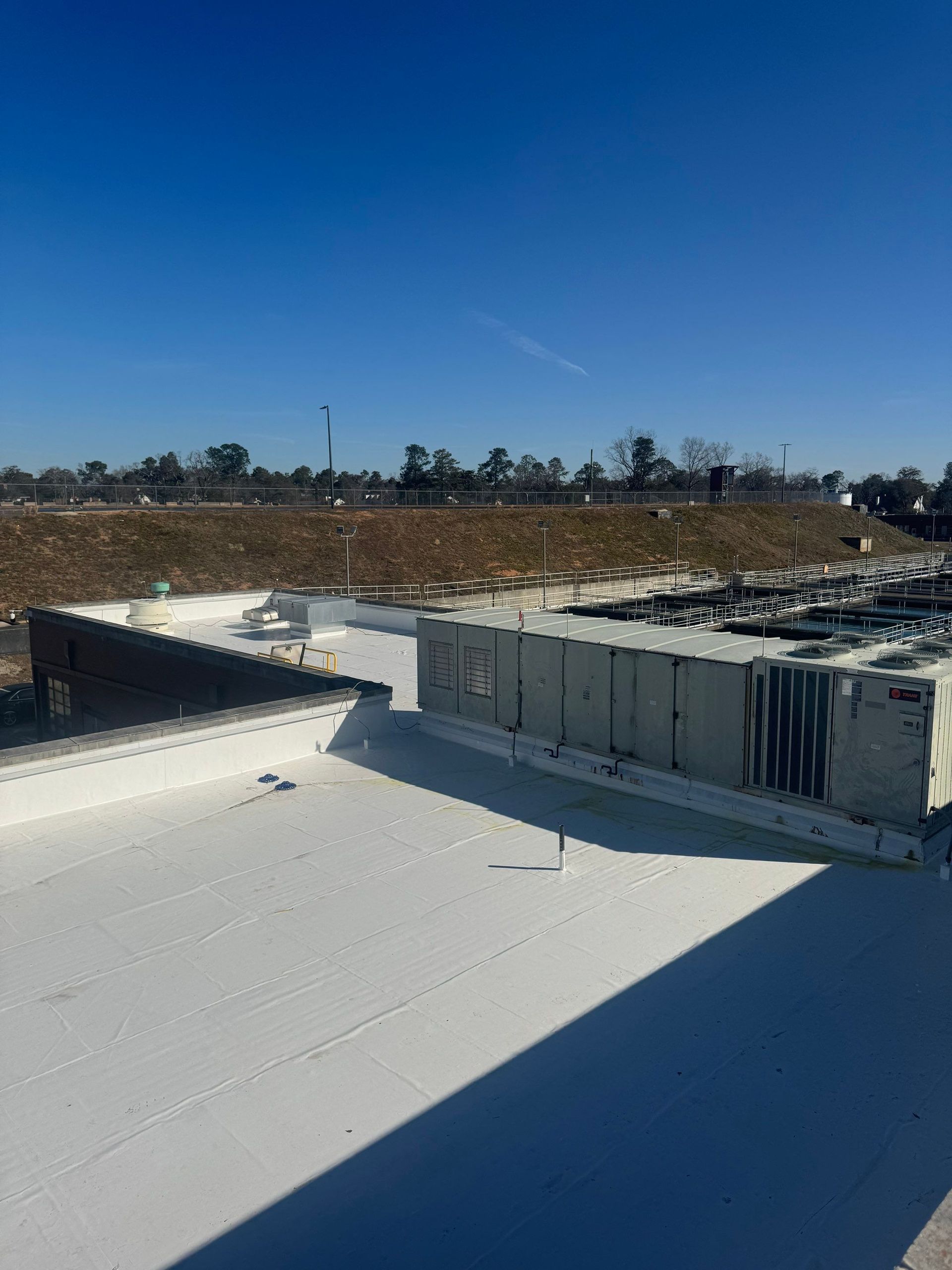 Workers covering a damaged roof with a blue tarp during sunset.