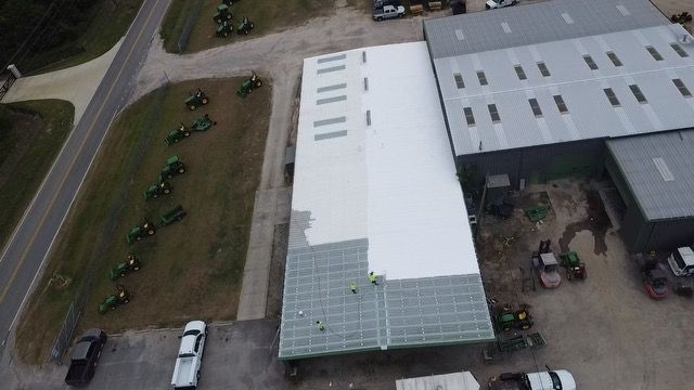 Roofers in blue shirts and hard hats repairing a roof at sunset.
