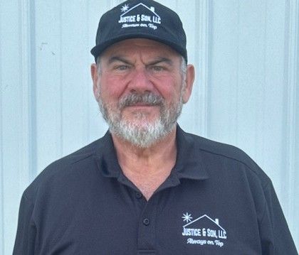 Man wearing a Justice & Son cap and polo shirt. He has a gray beard and is smiling.