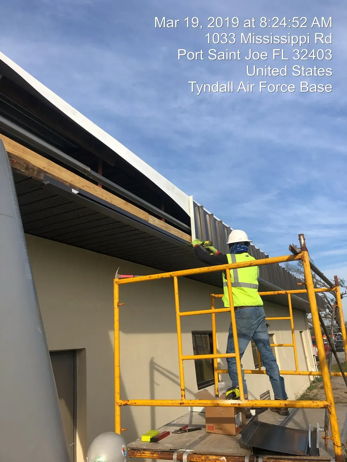 Worker on scaffolding repairing a building roof at Tyndall Air Force Base.