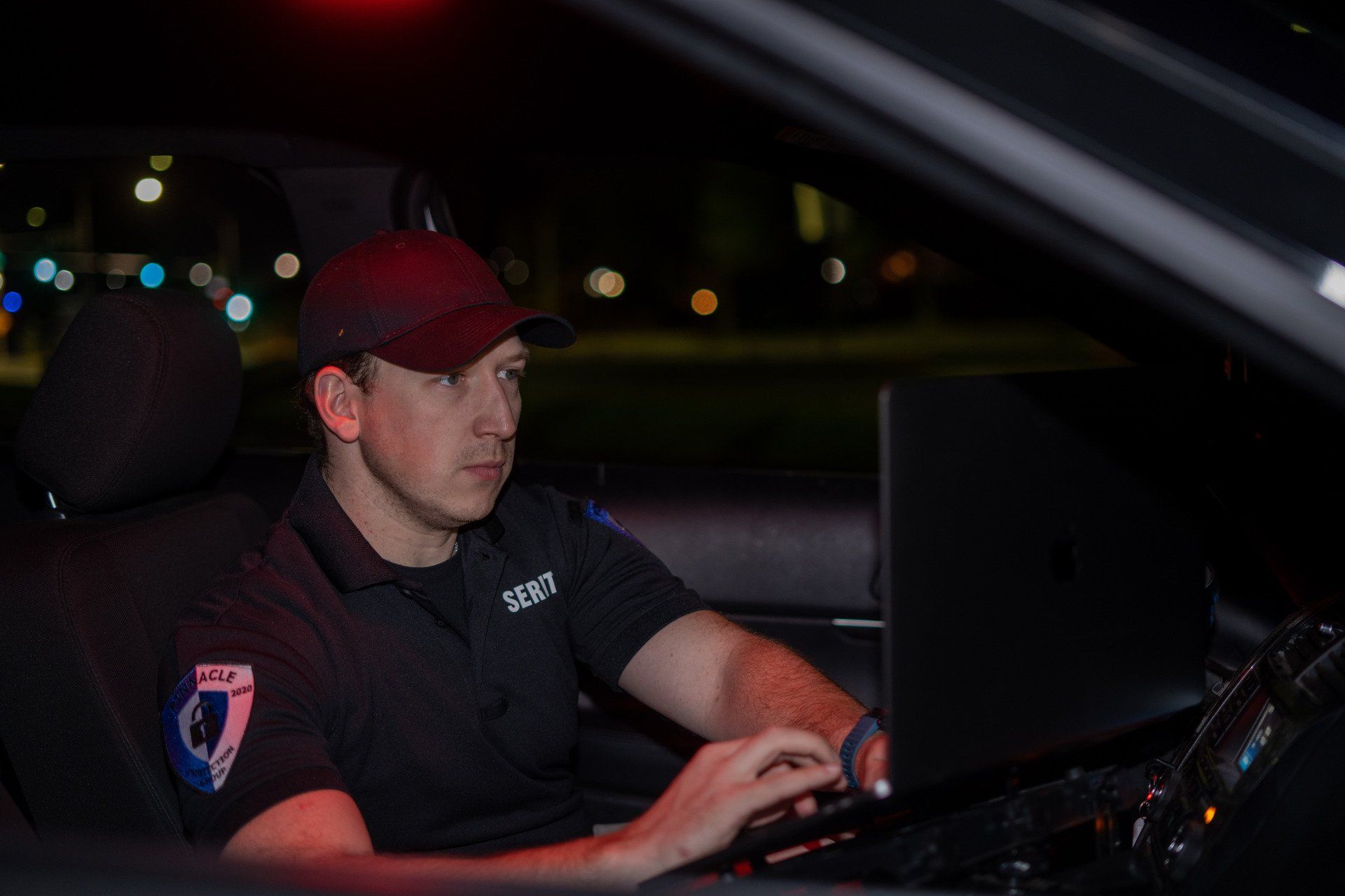a police officer is sitting in the driver 's seat of a car using a laptop computer .