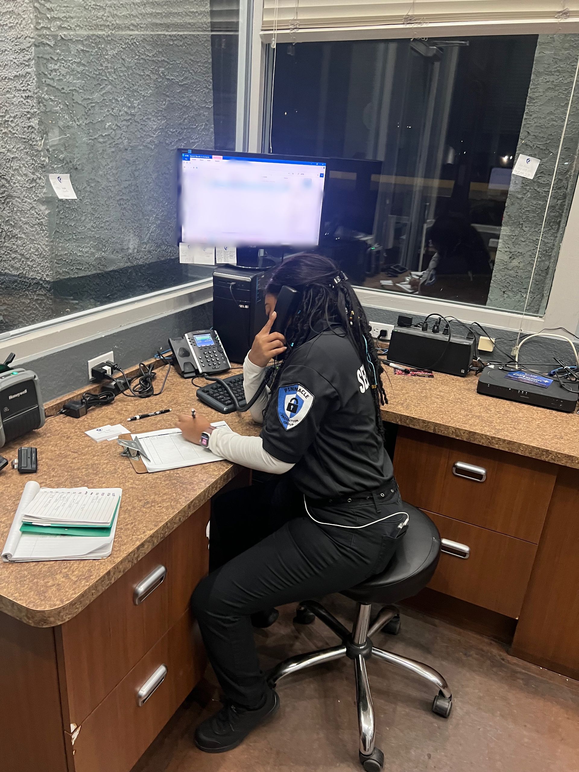 A woman is sitting at a desk in front of a computer talking on a phone.