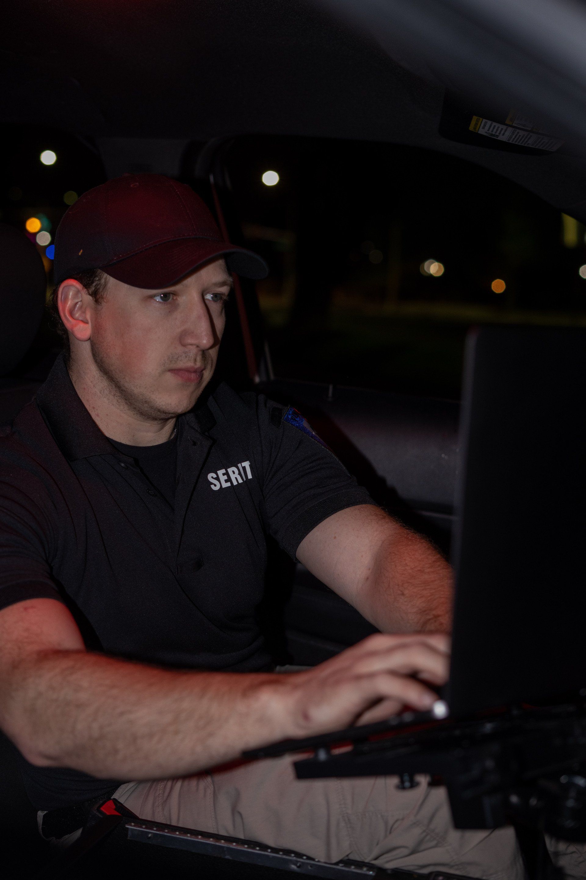a man is sitting in a car using a laptop computer .