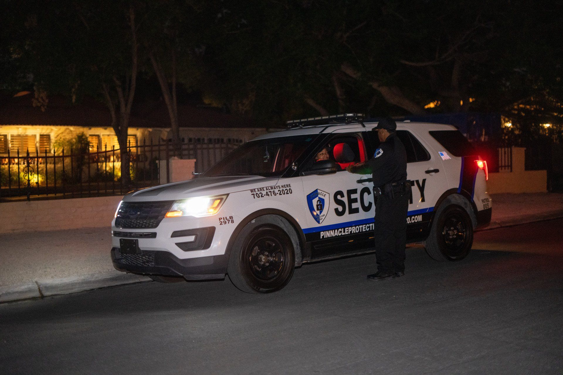 a security vehicle is parked on the side of the road at night .