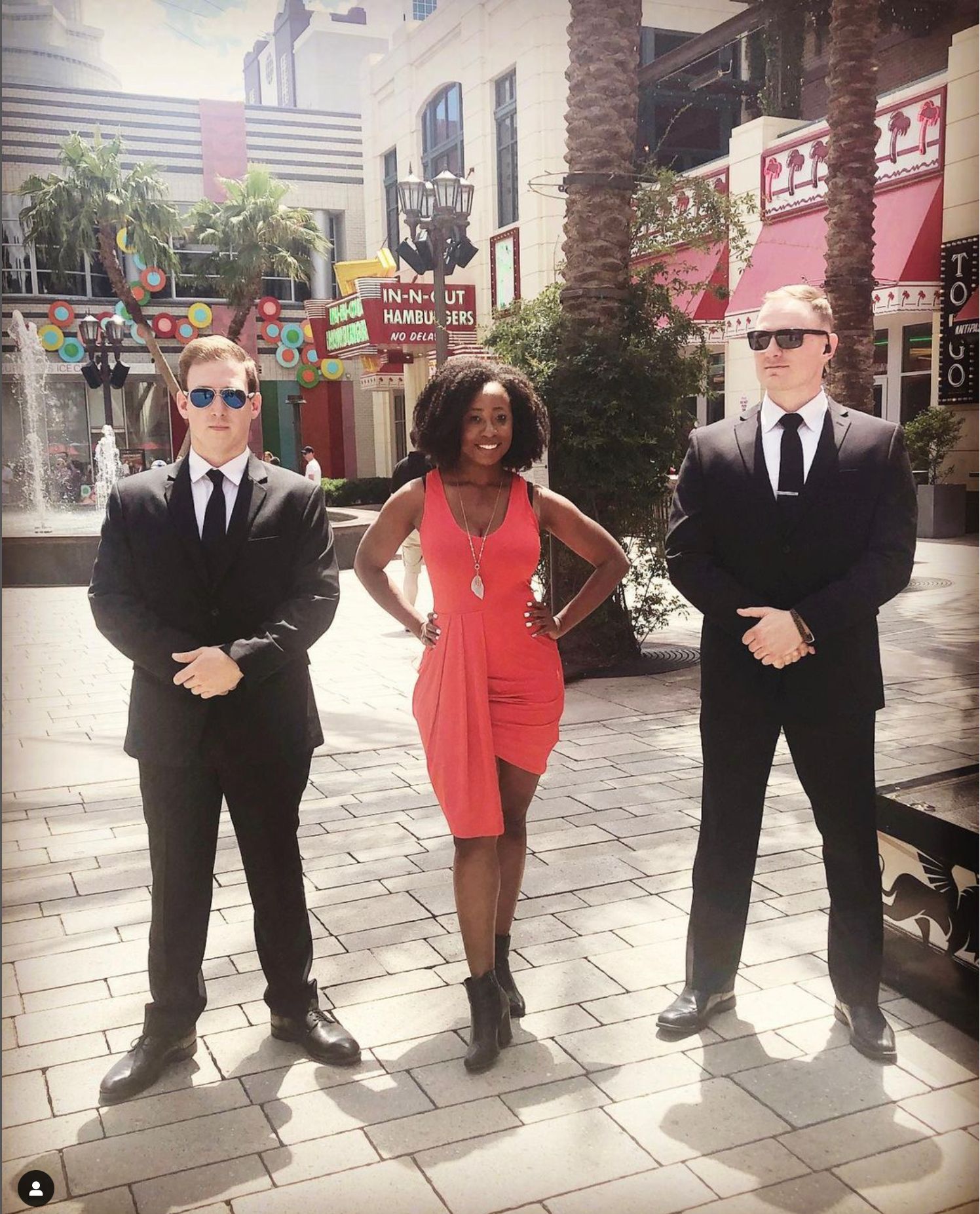 a woman in a red dress is standing between two men in suits .