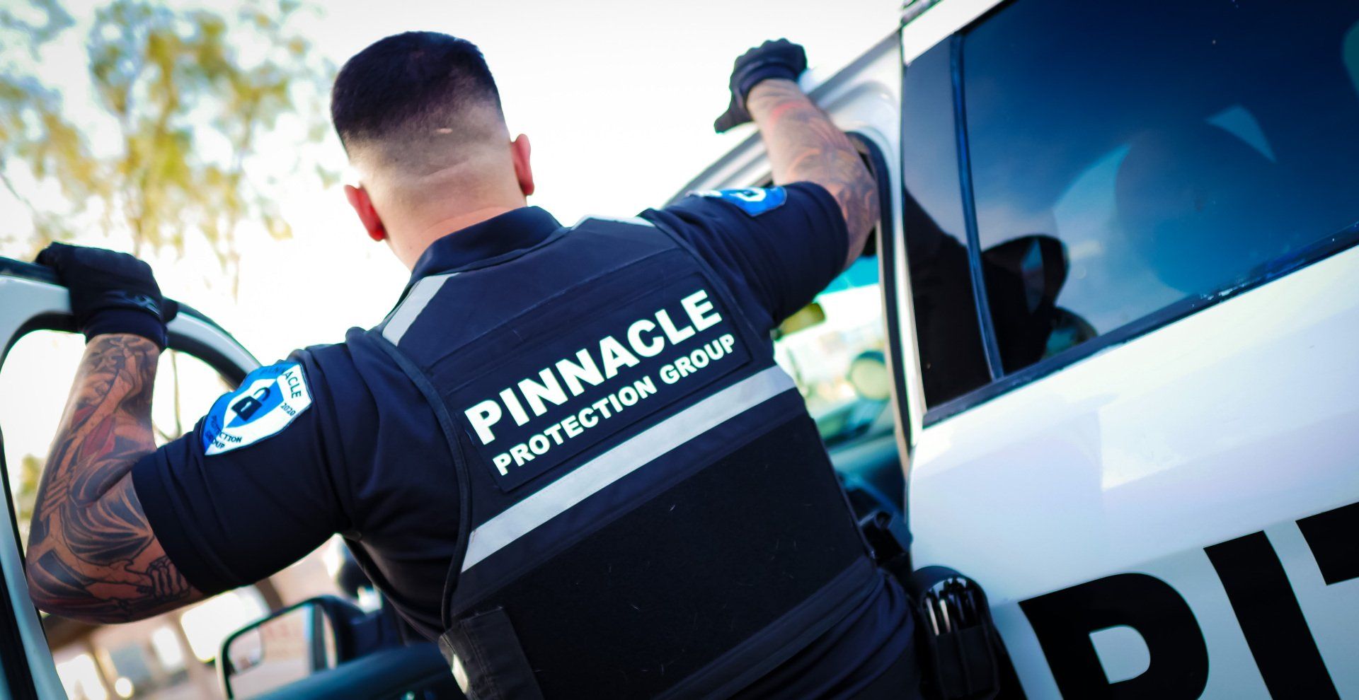 a man in a pinnacle protection group uniform is standing next to a white van .