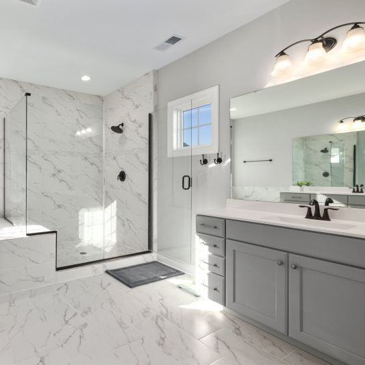 A bathroom with a bathtub , sinks , mirrors and a walk in shower.