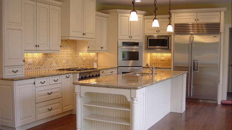 A kitchen with white cabinets , granite counter tops , stainless steel appliances and a large island.