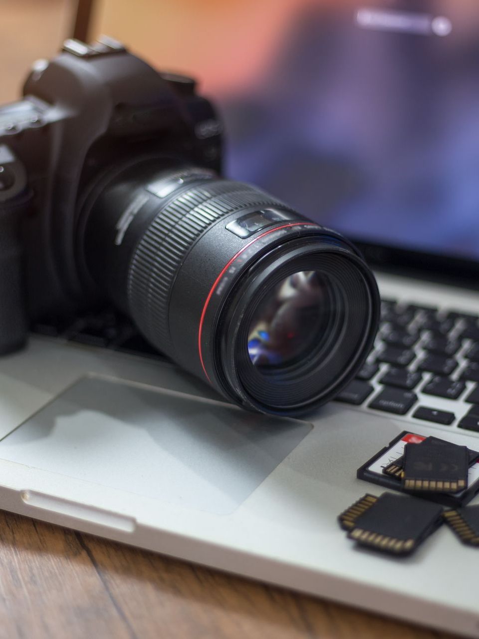 A canon camera is sitting on top of a laptop