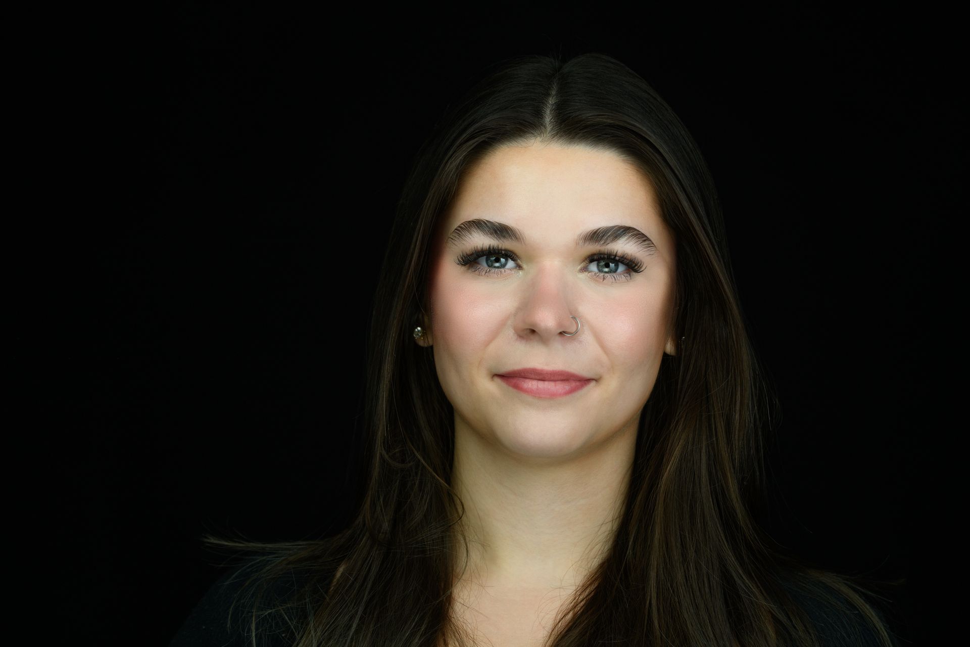 A young man with a tattoo on his wrist is covering his mouth with his hand.