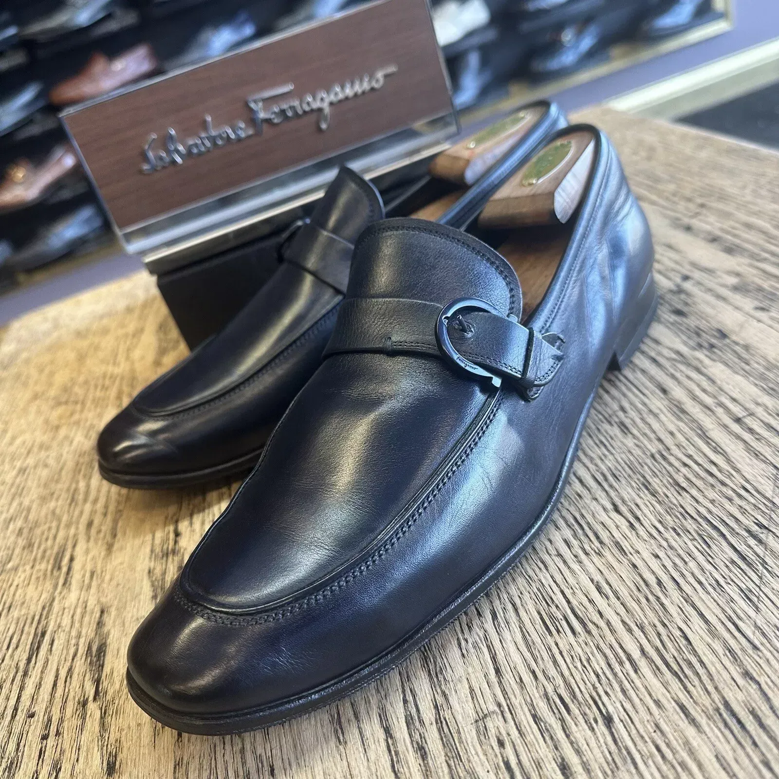 A pair of black ferragamo loafers sitting on a wooden table
