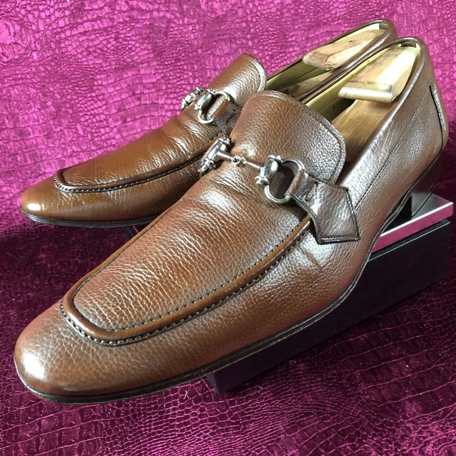 A pair of brown loafers are sitting on a purple surface.