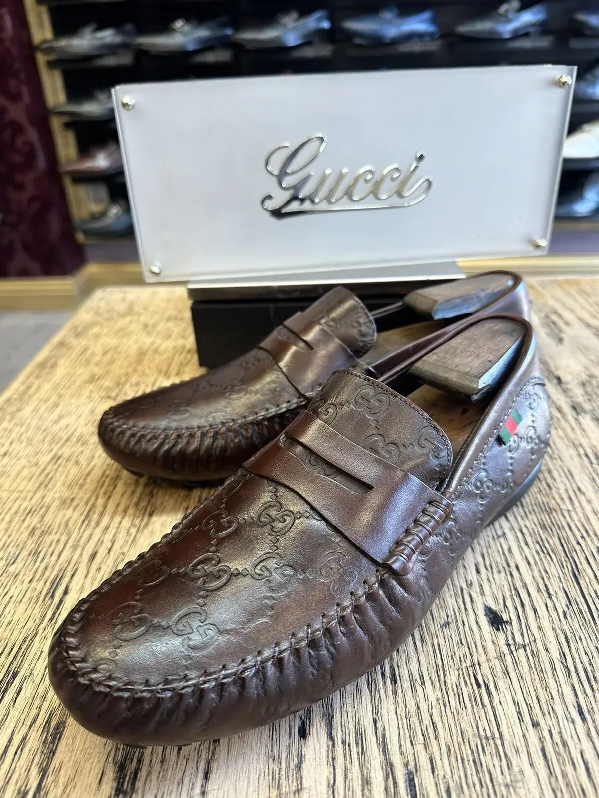 A pair of brown gucci loafers are sitting on a wooden table.
