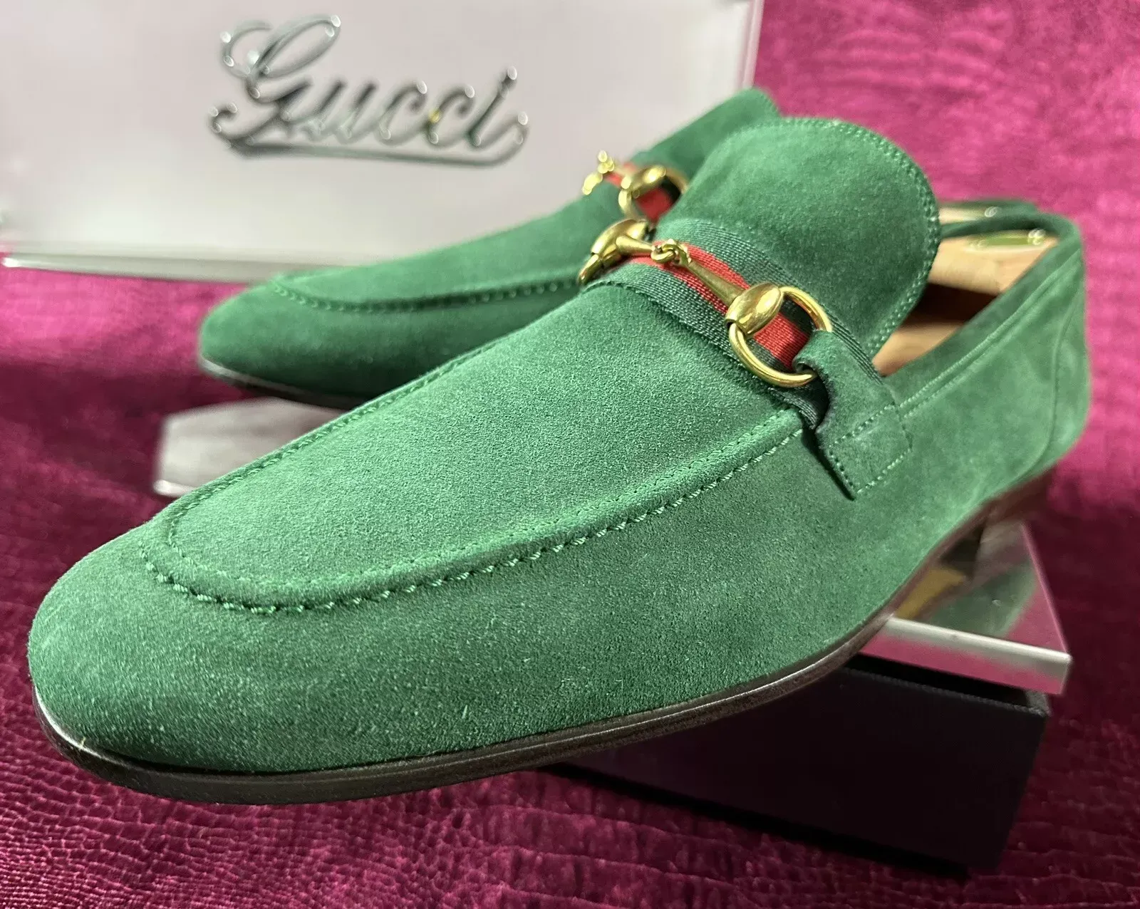 A pair of green gucci shoes are sitting on a purple surface