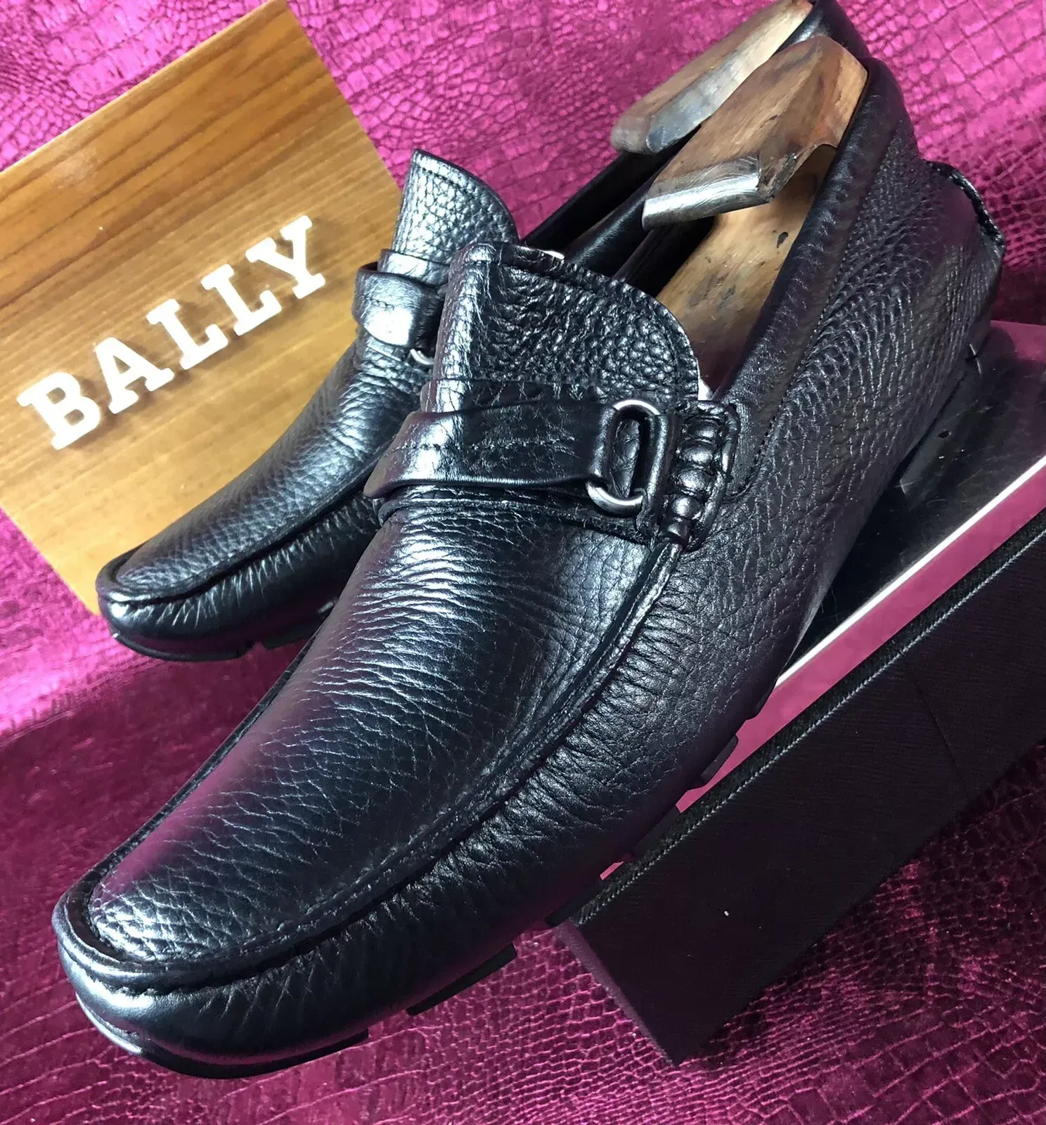A pair of black bally shoes sitting on top of a box
