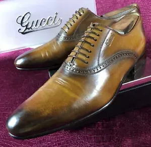 A pair of brown gucci shoes are sitting on a purple surface