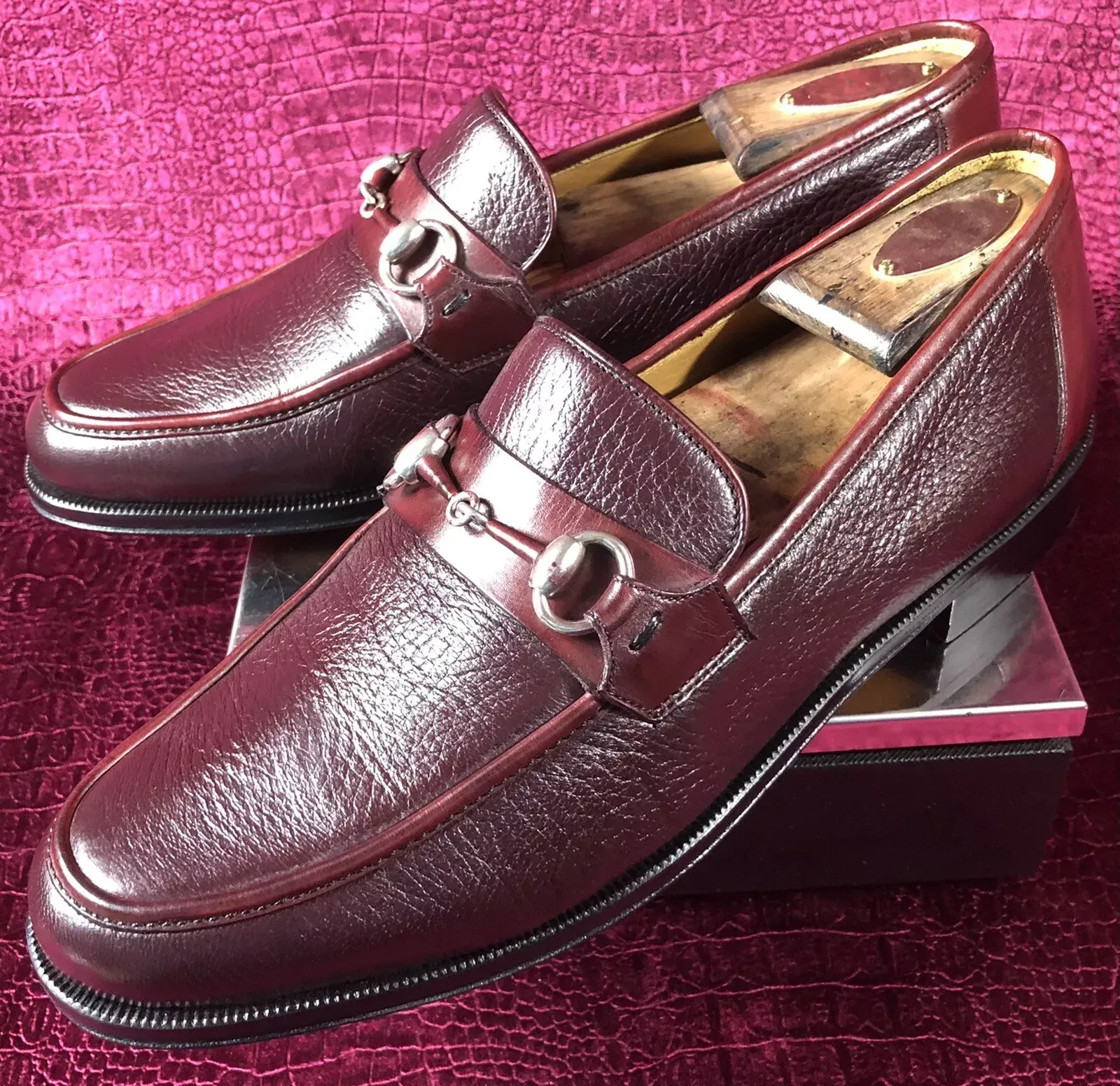 A pair of brown loafers are sitting on a purple surface