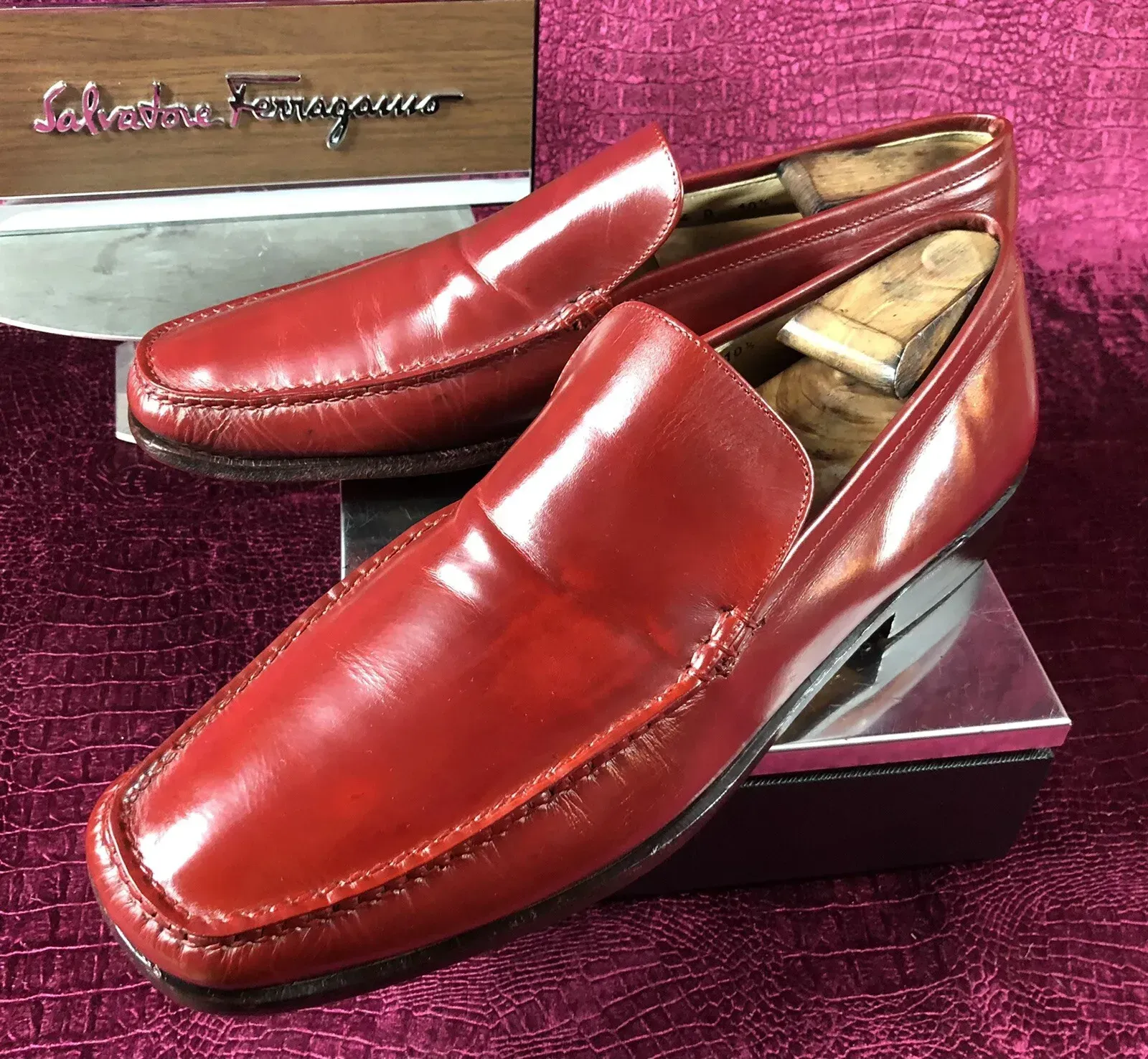 A pair of red ferragamo loafers are sitting on a purple surface