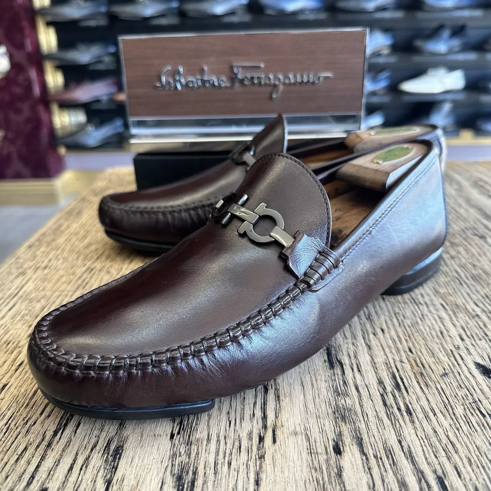 A pair of brown ferragamo loafers sitting on a wooden table